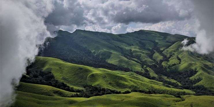 Rolling green hills beneath a cloudy sky, offering a tranquil and captivating sight.