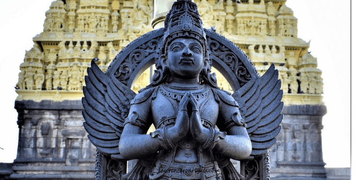 A statue of an Indian god standing in front of a temple, symbolizing spirituality and cultural heritage.