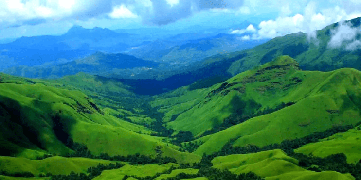 Green hills of Kerala, covered in lush vegetation, create a picturesque landscape in this captivating image.