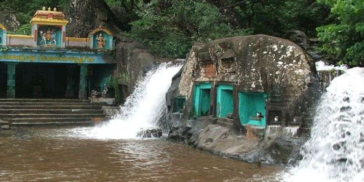 A serene temple surrounded by lush greenery, with a majestic waterfall cascading in front.