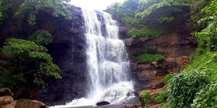 A picturesque waterfall nestled amidst vibrant green trees, creating a serene and captivating natural scene.