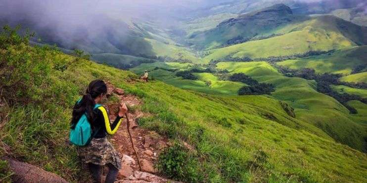 A woman hiking up a mountain in the rain, determined and focused on reaching the summit despite the challenging weather conditions.