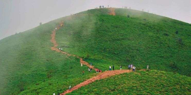 A cloudy day trek as hikers climb up a hill.