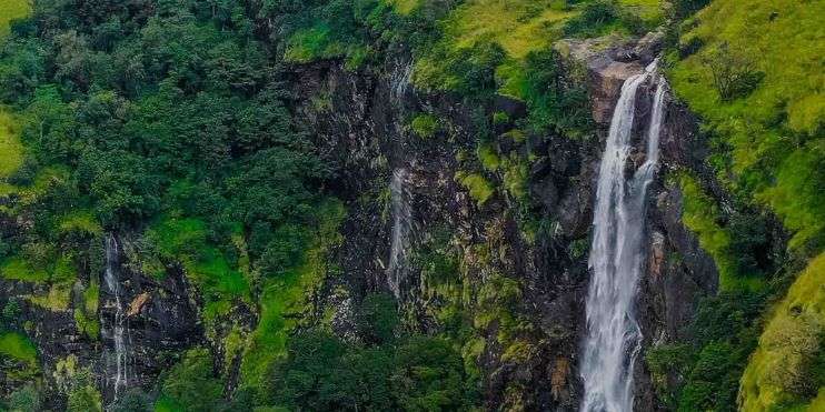 A waterfall surrounded by lush green vegetation at Bandaje Falls. Best Time to Visit Bandaje Falls.