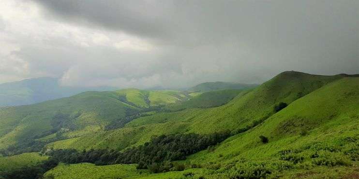 A scenic view of mountains from a hillside, with lush greenery in the foreground.