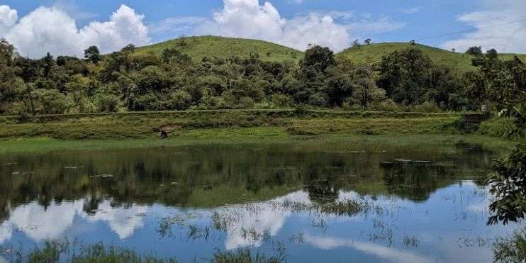 Scenic view of Devaramane Lake with a hill in the background