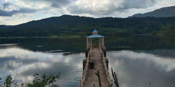 A small gazebo on a pier at Hirekolale Lake, Chikmagalur, surrounded by serene waters and picturesque landscapes.