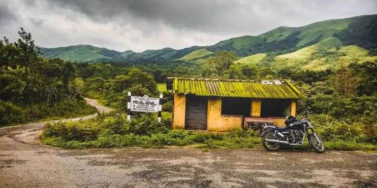  A motorcycle parked in front of a small shack at Devaramane, showcasing a glimpse of the area's history.