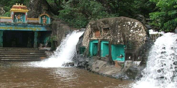 A stunning 122-meter waterfall cascading in front of a temple, surrounded by dense forests.