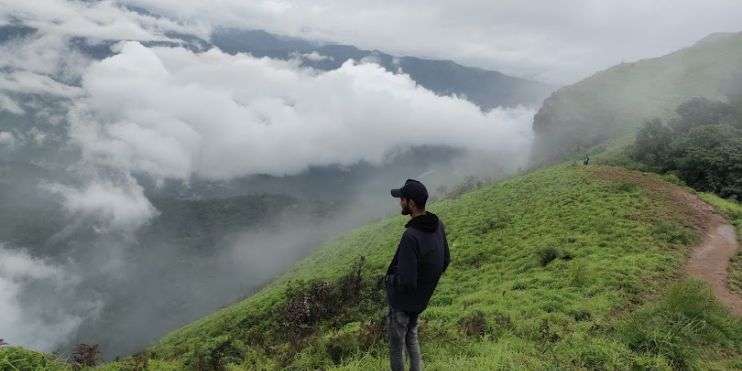 A scenic waterfall in the mountains surrounded by rocks and grass, part of the trek to Bandaje Falls with stunning Western Ghats views.