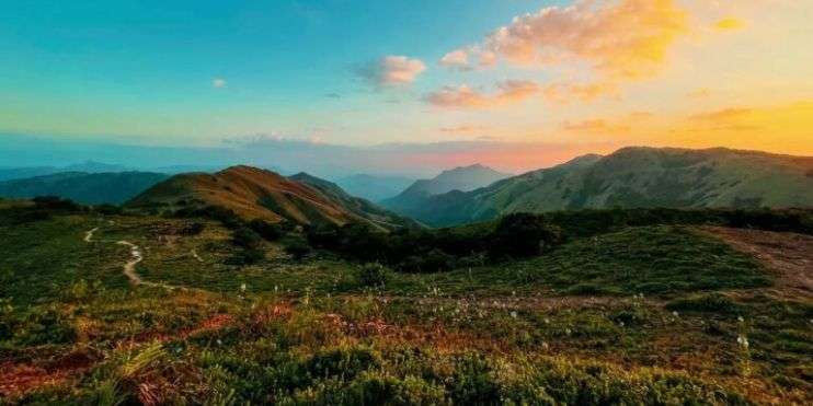 Sun setting over Western Ghats, creating a stunning silhouette of mountains against the colorful sky.