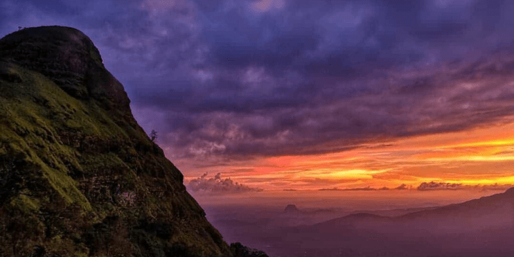 A stunning sunset showcasing vibrant colors and the scenic backdrop of the Ballalarayana Durga trekking area.