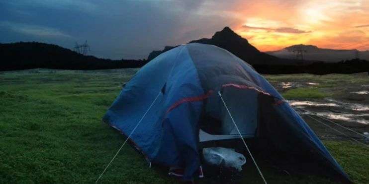 A tent is pitched on grassy terrain at sunset, creating a picturesque scene perfect for camping in the cooler months. 