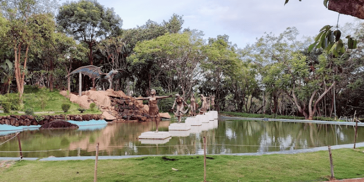 A serene pond featuring a large water slide and a tree, ideal for picnics and nature exploration in a tranquil park setting.