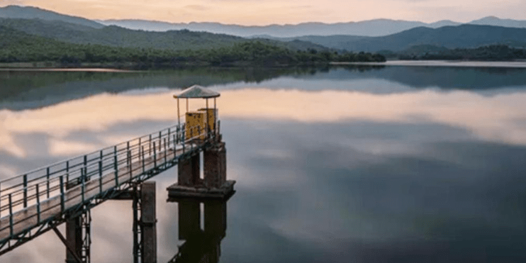 A scenic pier with a small bridge over Ayyanakere Lake, surrounded by mountains, ideal for recreation and sightseeing.