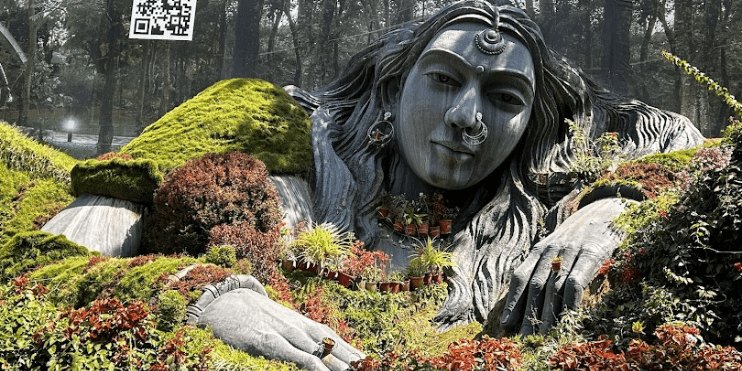 A statue of a woman stands gracefully in a lush garden, surrounded by vibrant plants at Mahatma Gandhi Park.