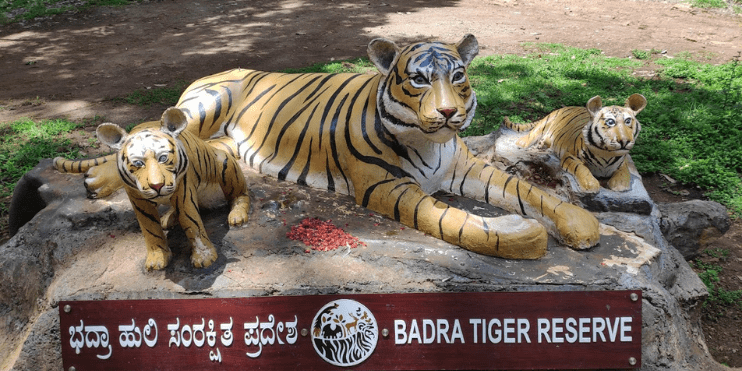 A statue of a tiger and two cubs perched on a rock, symbolizing wildlife conservation and natural beauty.