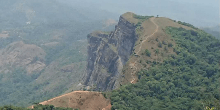 A scenic mountain road overlooking lush landscapes, symbolizing Chikmagalur's coffee culture and natural beauty.