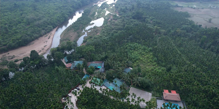 Aerial view of a river winding through a forest, with a house nestled among the trees, showcasing nature's tranquility.