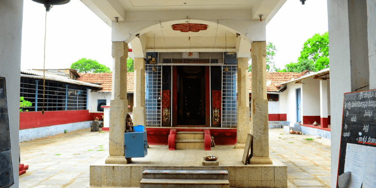 A small temple with a doorway and steps, surrounded by lush greenery, evoking calmness and reverence in Chikmagalur.