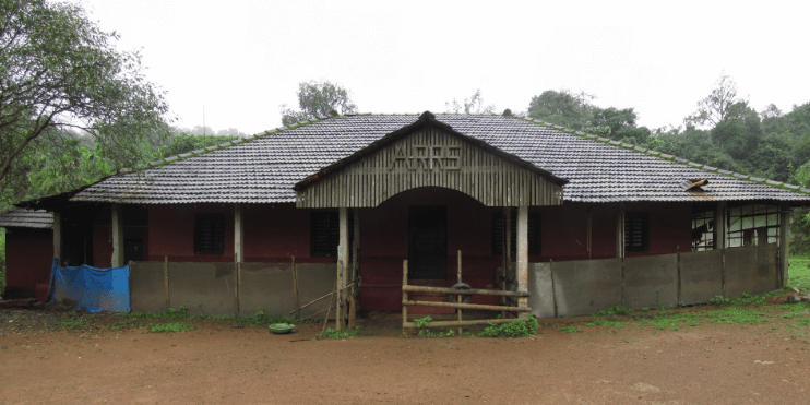 A small red house with a wooden roof nestled in a lush green environment, symbolizing harmony with nature.