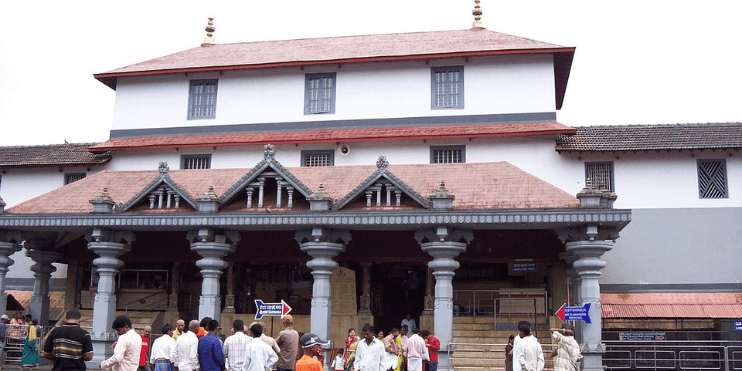 A diverse group of individuals gathered outside the Dharmasthala Manjunatha temple, showcasing its cultural significance.