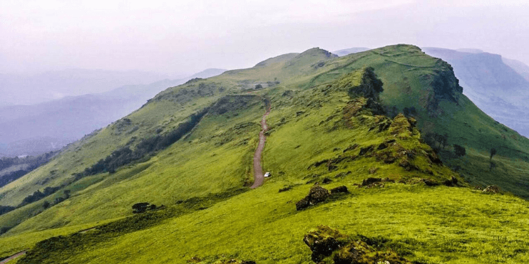 A winding road through a lush green mountain, inviting hikers to explore its scenic beauty and spiritual significance.