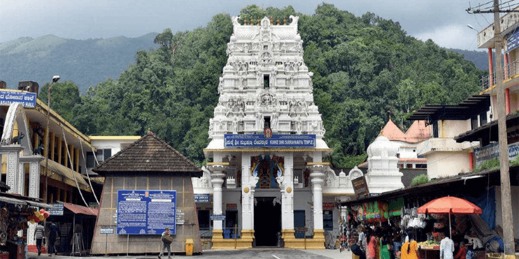 A white temple with a tall tower, located in a town amidst the Western Ghats, known for its spiritual significance.