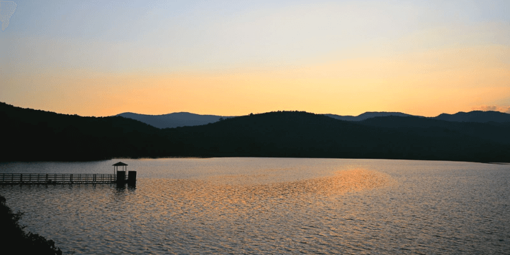 A serene lake with a dock and a mountain backdrop, perfect for picnics and boating in a tranquil setting.