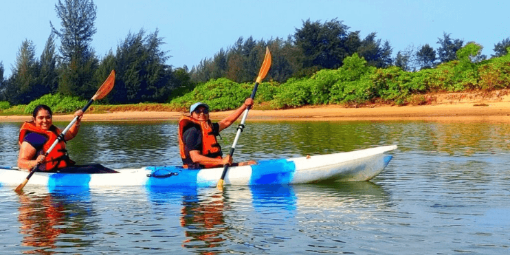 Two individuals paddle a kayak on tranquil waters, enjoying the scenic beauty of Yagachi Water Adventure Sports Center.