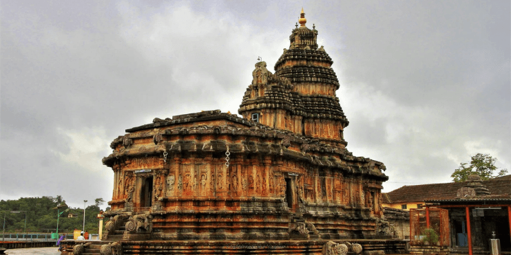 A stone temple with a tower, set by the riverside, offering a serene environment for meditation and reflection.