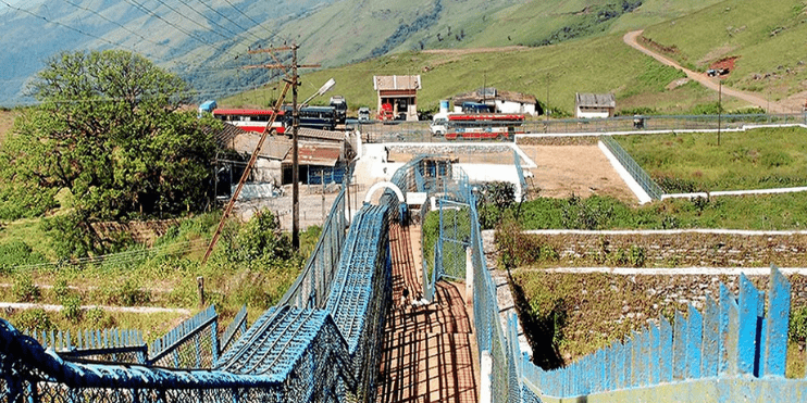 A suspension bridge spans a river, surrounded by majestic mountains, showcasing the region's natural beauty.