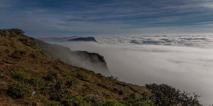 A breathtaking view of clouds from a mountain peak, showcasing nature's beauty in Chikmagalur's serene landscape.