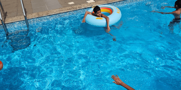 A man and a child engaged in playful activities in a pool, representing the fun experiences available for all ages at Bynekaadu.