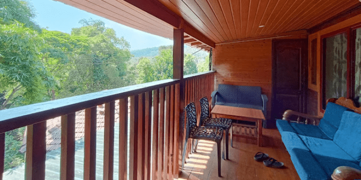 A luxurious balcony featuring a blue couch and elegant wooden railing, epitomizing top-tier comfort and style.