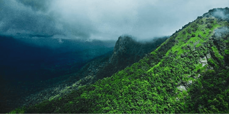 Aerial view of majestic mountains surrounded by clouds, showcasing the beauty of nature's untouched landscapes.