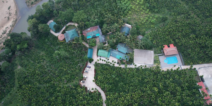 Aerial view of a house nestled among lush trees, promoting Bynekaadu Resort in Kalasa for an extended stay.