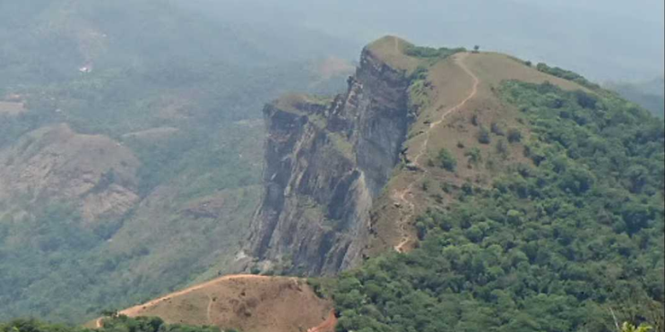 A picturesque mountain featuring a road on its summit, illustrating the route to Inam Dattathreya Peeta from Chikmagalur.