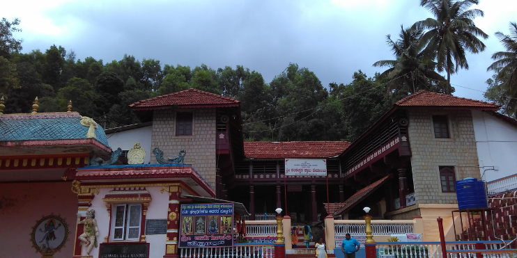 A picturesque view of Kalasa Temple, showcasing its vibrant red roof and elegant white fence in a serene landscape.