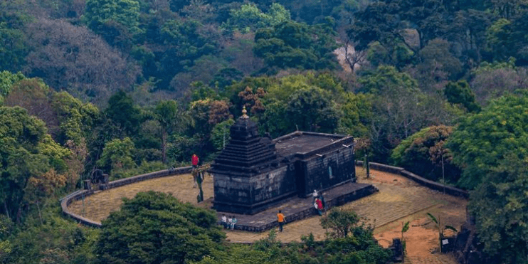 Aerial view of Bettada Byraveshwara Temple surrounded by dense forest, showcasing the beauty of nature and tranquility.