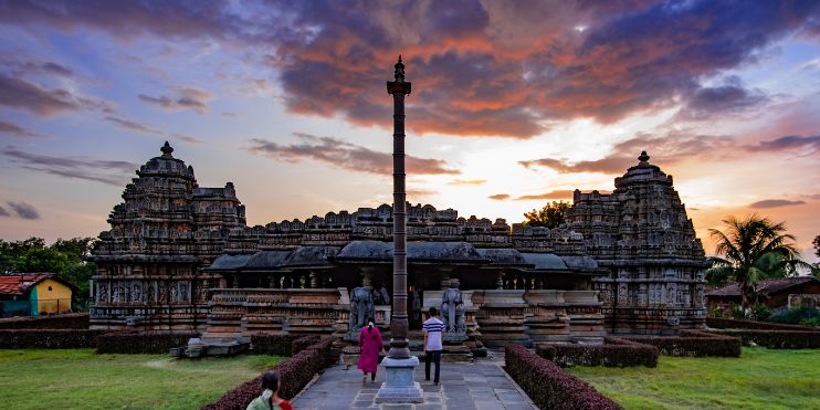 Sunset over the Hampi temple in Karnataka, casting warm hues on the ancient architecture and surrounding landscape.