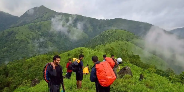 A group of hikers navigating a mountain trail, surrounded by lush greenery and scenic views in Sakleshpur.
