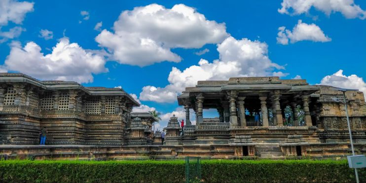 Chennakeshava Temple in Belur, India, features intricate sculptures against a backdrop of blue sky and clouds.