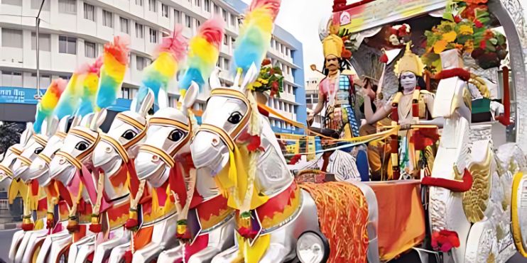 A large, colorful horse carriage adorned with vibrant decorations, showcased during the Hoysala Mahotsava festival.