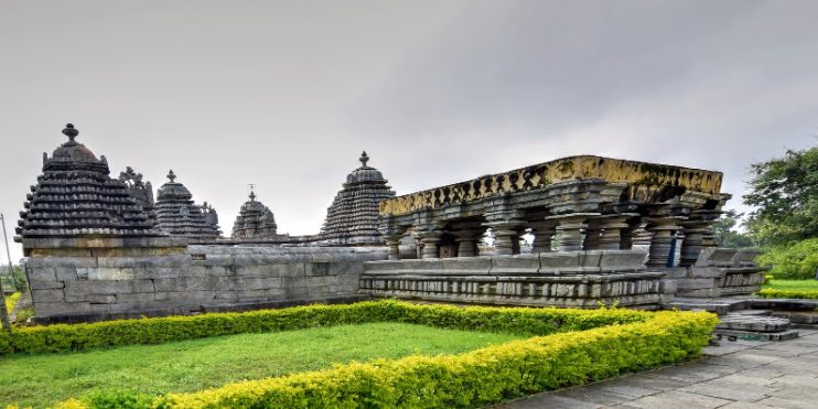Hoysaleswara and Shantaleswara Temples surrounded by lush green grass, showcasing intricate carvings and a serene atmosphere.