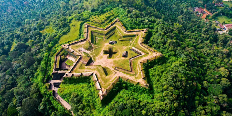 Aerial view of Manjarabad Fort, a star-shaped fortress surrounded by lush green forest, showcasing its historical significance.