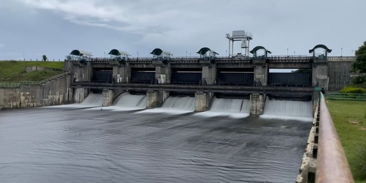 A large dam with water cascading over it, surrounded by scenic hills, ideal for picnics and boating near Belur.