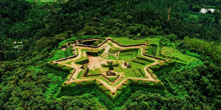 Aerial view of a star-shaped castle surrounded by lush green forest in Sakleshpur, a scenic gem in the Western Ghats.