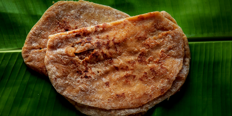 A banana leaf holds two pieces of bread, symbolizing the sweet treats of Chikmagalur's coffee culture.
